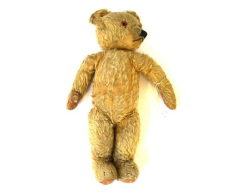 A pre-war gold plush Merrythought teddy bear
With glass button eyes, button to left ear, with articulated limbs height 52cm.