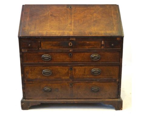 An early 18th Century walnut bureau
The hinged sloping fall front cross banded and with herringbone inlay, enclosing an attra