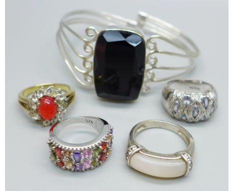 Four silver rings and a bangle 