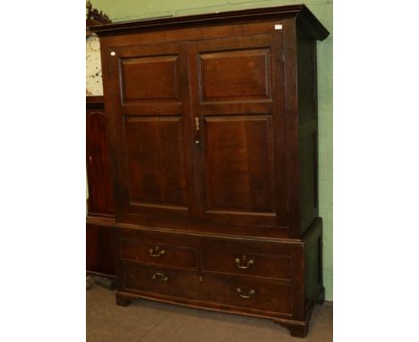 A mid 18th century oak press cupboard, the bold cornice above fielded panel cupboard doors enclosing a brass hanging rail, th