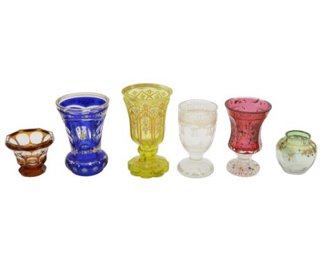 Six late 19th century Bohemian glass spa beakers and other glass,first a ruby glass goblet raised on clear glass foot, enamel
