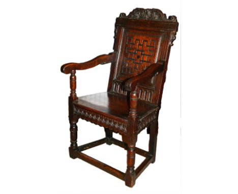 A 17th century carved oak Wainscot armchair the rectangular geometric carved panelled back with scroll carved crest rail, hav