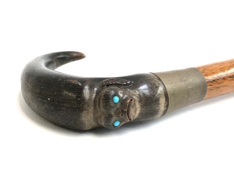 A walking stick with horn handle carved with the mask of a Pekingese dog set with turquoise coloured eyes, 90cmL 