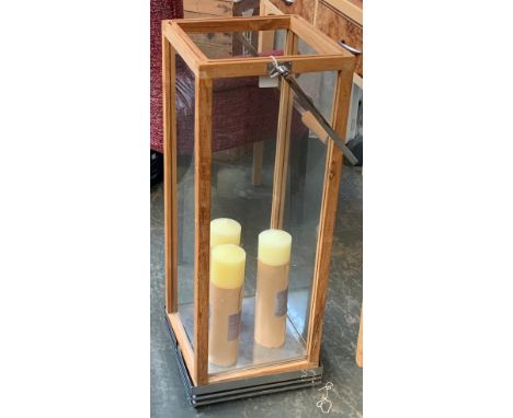 A Madeira teak and chrome lantern, containing three large Watts &amp; Co. candles, 82cmH 