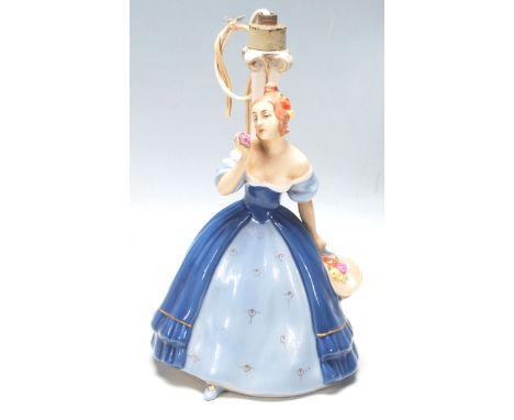 A vintage Royal Dux Art Deco porcelain figurine table lamp, having a ceramic lamp stem and a young lady dressed in blue at th