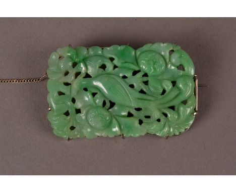 A Chinese Art Deco period jade medallion, set as a brooch in silver wire mount, in hues of opaque green, and carved with feng