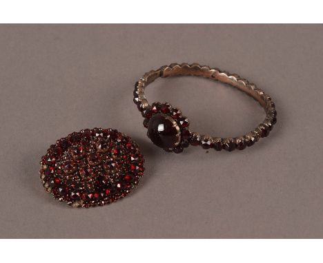 A Victorian garnet brooch and bangle, the oval brooch with gold back, lacking several small stones, the bracelet with large c