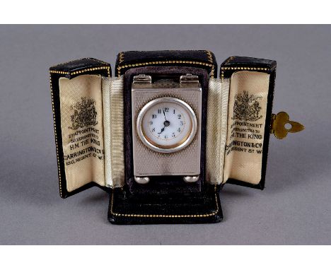 A fine miniature George V silver travel clock by William Comyns, in a fitted case from Carrington &amp; Co, in the form of a 