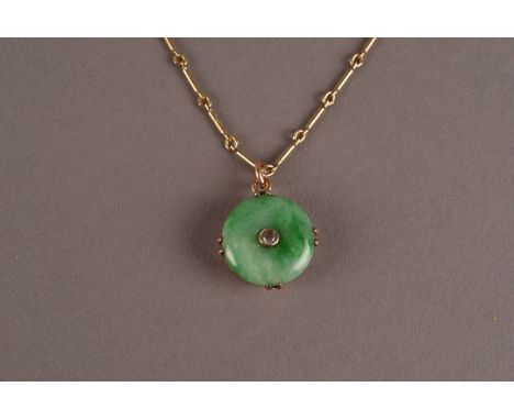 A pretty Edwardian period jade pendant, the pierced green hardstone disc centred with an old cut shaped clear stone in a yell