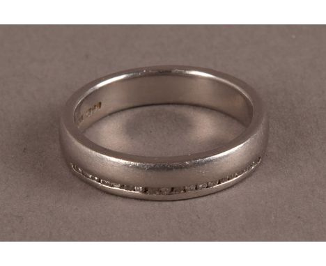 A modern platinum and diamond set wedding band, the thick heavy band with a row of small channel set brilliant cuts, hallmark