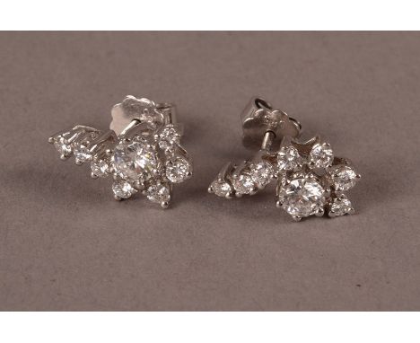 A pair of modern 14ct white gold and diamond earrings, in the Art Deco taste, having a sweep of brilliant cuts and centred wi