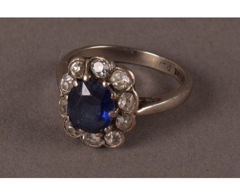 A vintage 18ct white gold sapphire and diamond cluster ring, having an oval cut blue stone surrounded by old cuts in platinum