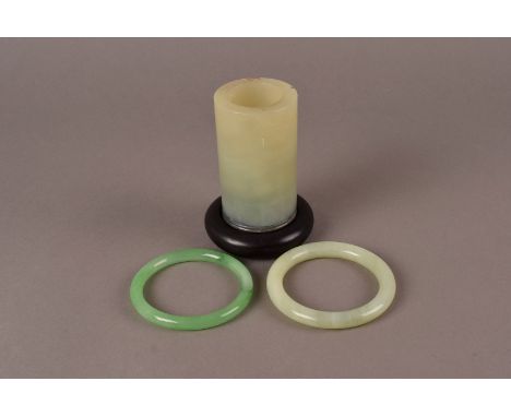 A pair of jade bangles, one celadon jade, the other a brighter green, together with a celadon jade sleeve vase 9.5cm H, on st