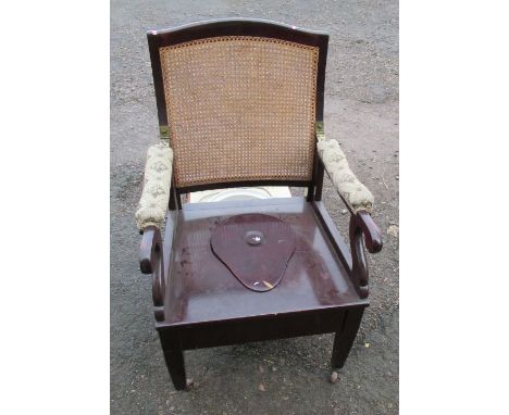 A 19th century Carters mahogany and cane back commode chair, with hinged drop down arms, having a shaped seat cover