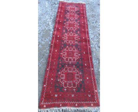 A 1950s red ground runner, with multi colours, 320cm x 110cm