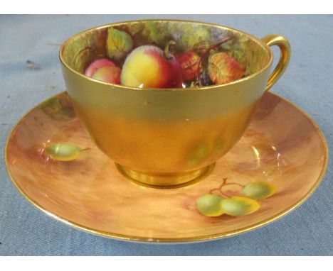 A Royal Worcester tea cup and saucer, painted to the interior of the cup with fruit by W H Austin, the saucer decorated fruit