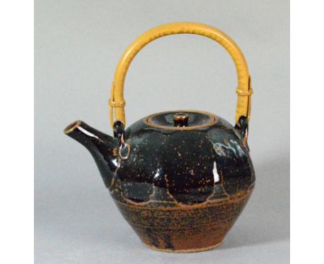 WILLIAM MARSHALL (1923-2007) for Leach Pottery; a cut-sided stoneware teapot with cane handle, covered in tenmoku breaking to