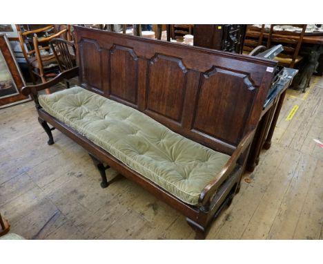 (THH) An 18th century oak settle,&nbsp;with fielded four panel back above webbed seat flanked by open arms, 183cm wide. 