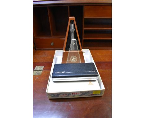 Two cased Heine otoscopes; together with a metronome.&nbsp; 