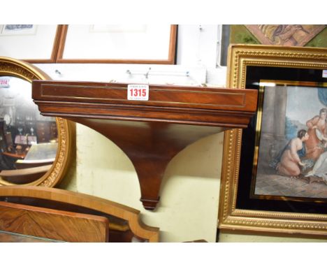 A Regency style mahogany and brass line inlaid clock bracket, with concealed lateral key drawer, 34cm wide. 