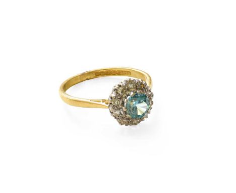 An 18 Carat Gold Blue Zircon and Diamond Cluster Ring, the round cut blue zircon within a border of eight-cut diamonds in whi