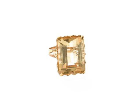 A Citrine Ring, the emerald-cut citrine in a yellow claw setting, with a rope twist decorated gallery, on a double row shank,