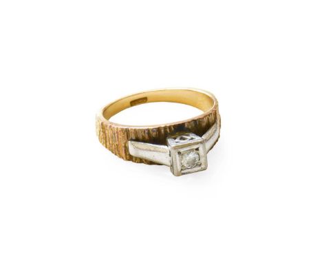A Diamond Solitaire Ring, the round brilliant cut diamond in a white square setting, to a yellow textured band, finger size M