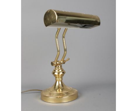A vintage brass articulated desk light with cylindrical curved shade.  In working order.