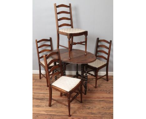 An oak drop leaf dining table with barley twist gateleg support along with four ladder back dining chairs.  