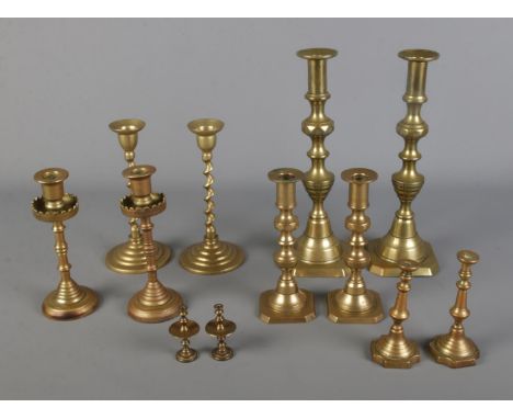 A collection of brass candlestick pairs of varying sizes to include twisted stem examples.  