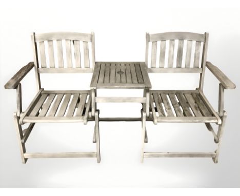 A teak two seater garden bench, incorporating a central table, 155 cm wide.