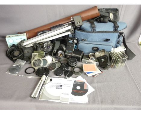 AN OLYMPUS OM10 SLR CAMERA, additional lenses, filters and associated equipment with a canvas carry bag and tripod stand