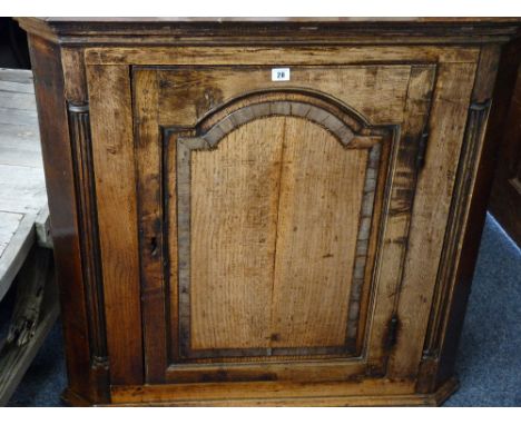 AN ANTIQUE OAK WALL HANGING CORNER CUPBOARD single door with cross banded panel detail and quarter cut reeded flanking column