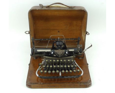 A Blickensderfer No. 7 typewriter, circa 1900, in an oak case with bentwood lid having a serpentine front, pre qwerty keyboar