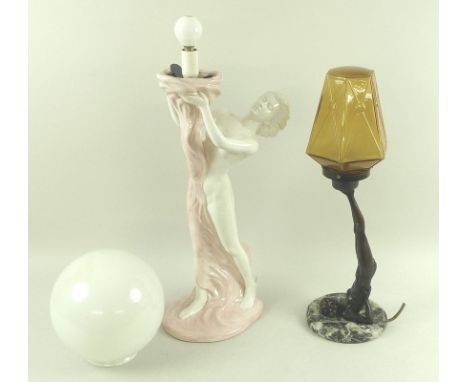 A pair of Art Deco style lamps, one a model of a nude supporting an amber globe with her feet, and an Italian ceramic figural