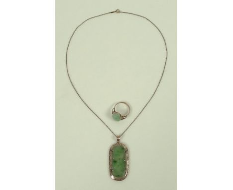 A 14ct gold and jade pendant, the flat apple jade lozenge carved with lotus blossom set into a pierced scroll mount, on a 14c