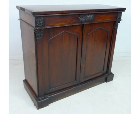 An early 19th century mahogany chiffonier, frieze drawer with carved rosettes to each end, over twin arched panel doors, flan