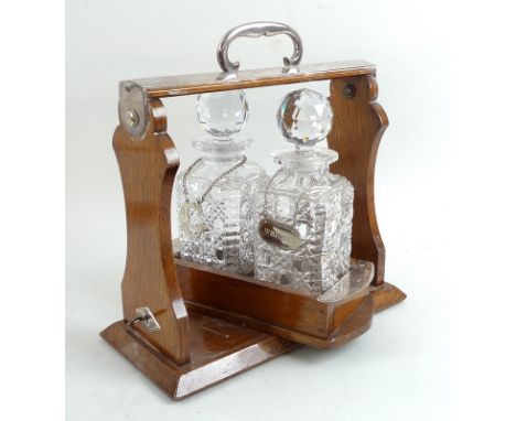 An oak and silver plated tantalus, with swivel mechanism, the plated sides each marked with the number 189, complete with loc