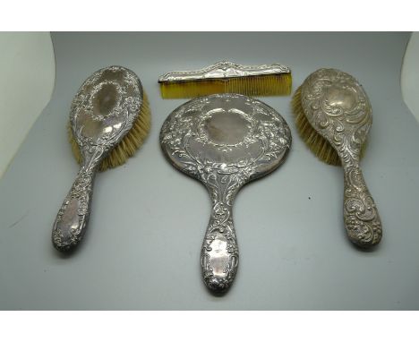 A silver backed mirror, two brushes and a comb 