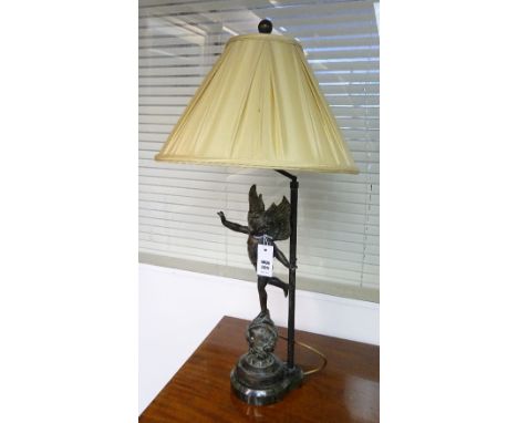 A bronze table lamp with shade, in the form of a winged putti, standing on spherical stand, raised on marble base, 84cm high