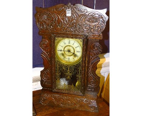 A late Victorian mantel clock, with foliate carved decoration to the case around white enamel dial with Roman numerals, the g