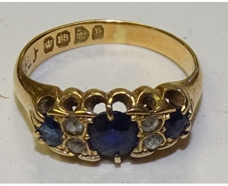 A Victorian 18ct gold sapphire and diamond ring, the large central oval cut sapphire flanked by two small old cut diamonds to