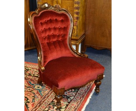 A Victorian mahogany framed gent's parlour armchair, upholstered in later red buttonback velour, raised on turned supports wi