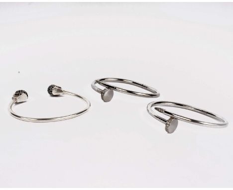 Two white metal bangles marked 750 Cartier together with a further white metal bangle. 