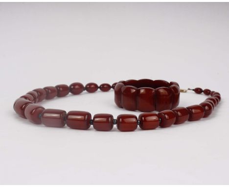A string of dark amber or Bakelite beads together with a matching plaque bracelet. 