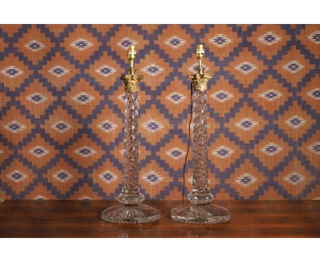 A pair of facet cut glass table lamps, modern, with a gilt bronze Corinthian capital, leading to a facet cut stem, raised on 