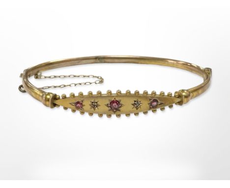 An antique 9ct yellow gold bangle set with three rubies and two small diamonds, internal dimensions 6 cm x 4.7 cm. CONDITION 