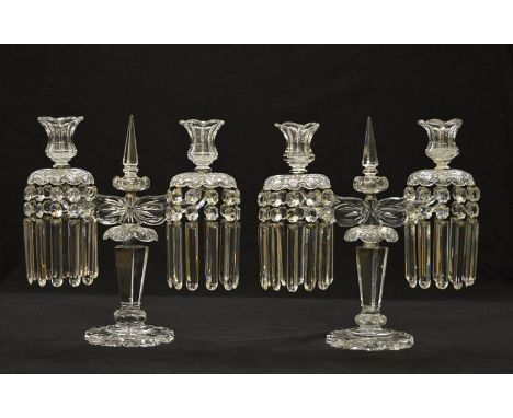 A pair of cut and moulded clear glass twin light lustre candelabrathe upward scrolling arms with lotus urn nozzles and scallo