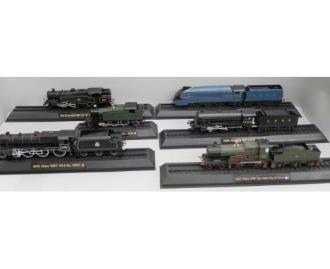 A box of plastic model rail locomotives on plinths 
