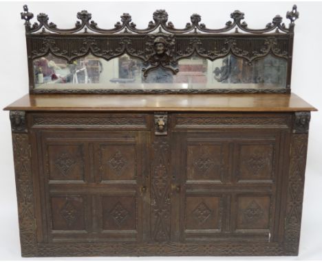 A 17TH CENTURY DESIGN OAK MIRROR BACK SIDEBOARD applied with masks, above a pair of panelled doors with carved geometric patt